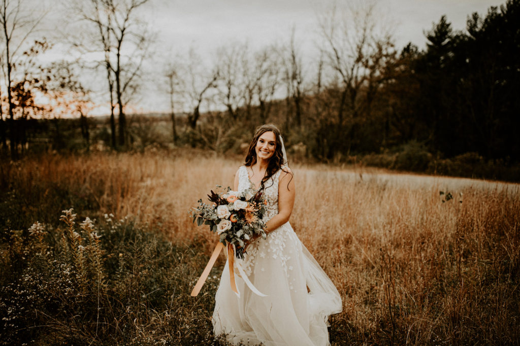 bride in open field with large bouquet
