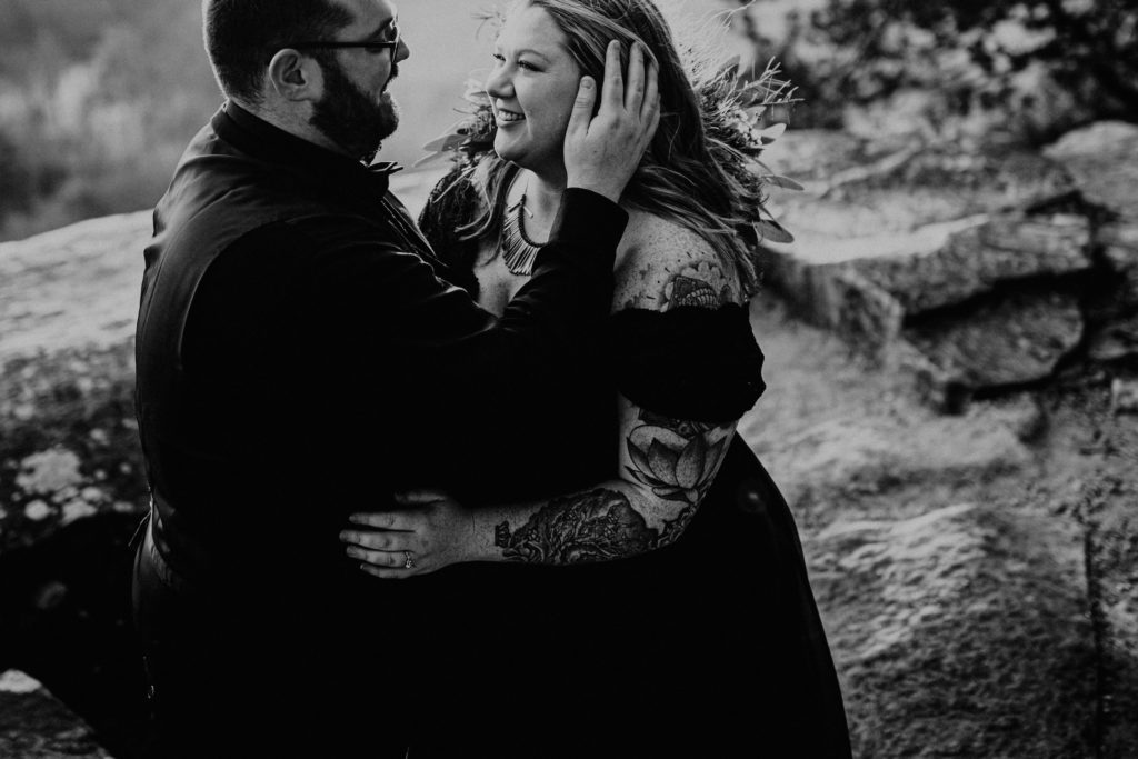 black and white photo of bride in groom in all black dress groom holding brides face