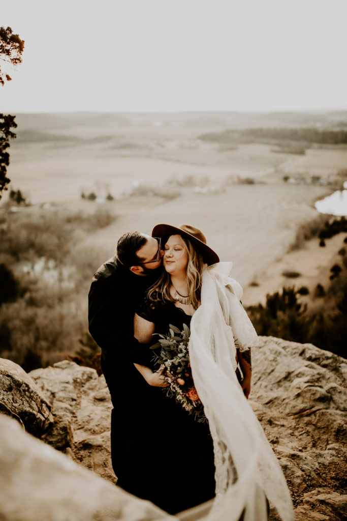 groom kissing bride while eloping in Wisconsin on top of Gibraltar rock