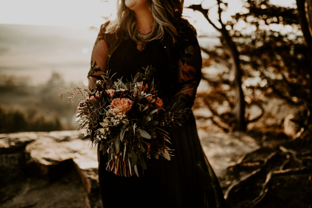 up close photo of bride with black wedding dress holding large bouquet