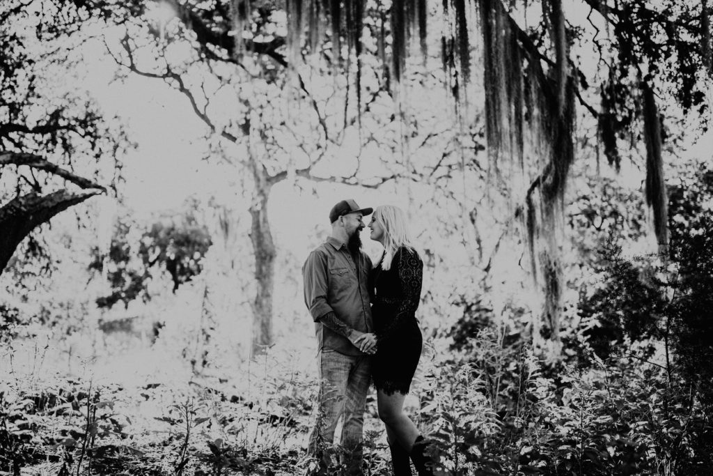 black and white photo of couple standing under the Texas desert and Spanish moss