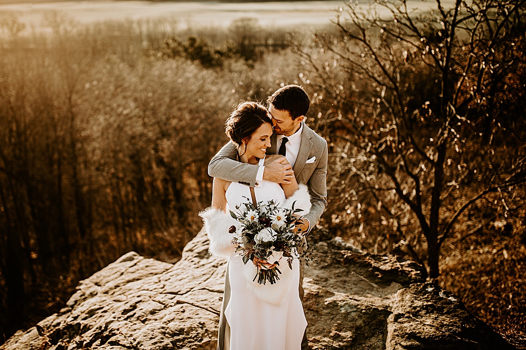 bride and groom embrace on a bluff