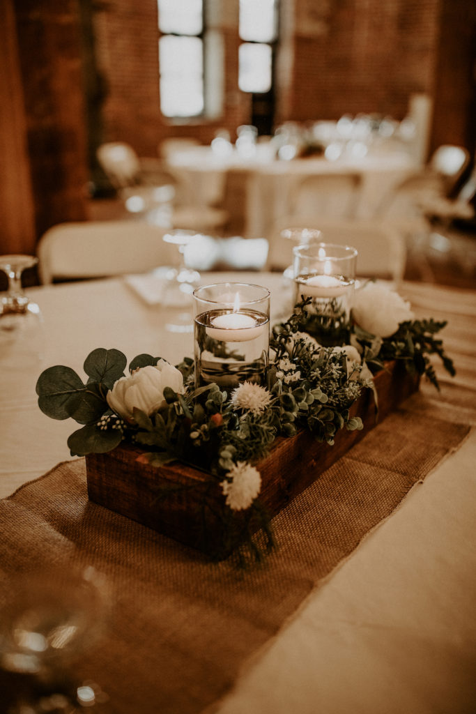 Wedding table centerpiece with burlap running cloth wooden box and floral bouquets with candles