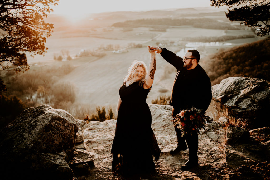 moody photos of couple on large rock in Wisconsin with open valley views below