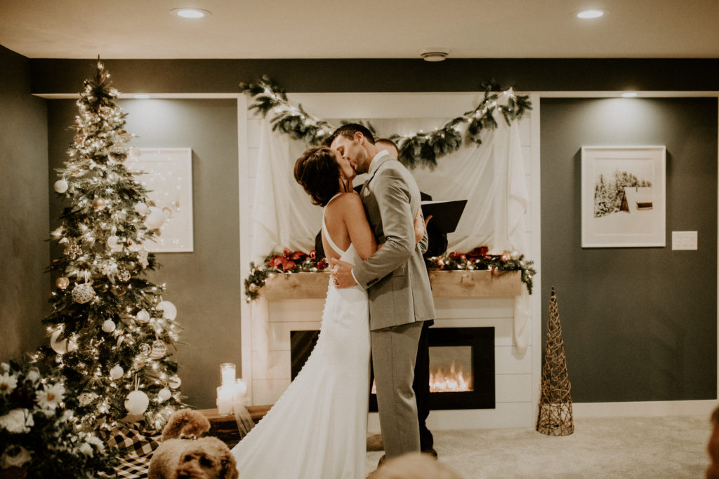 bride and groom kissing on wedding day in their living room ceremony
