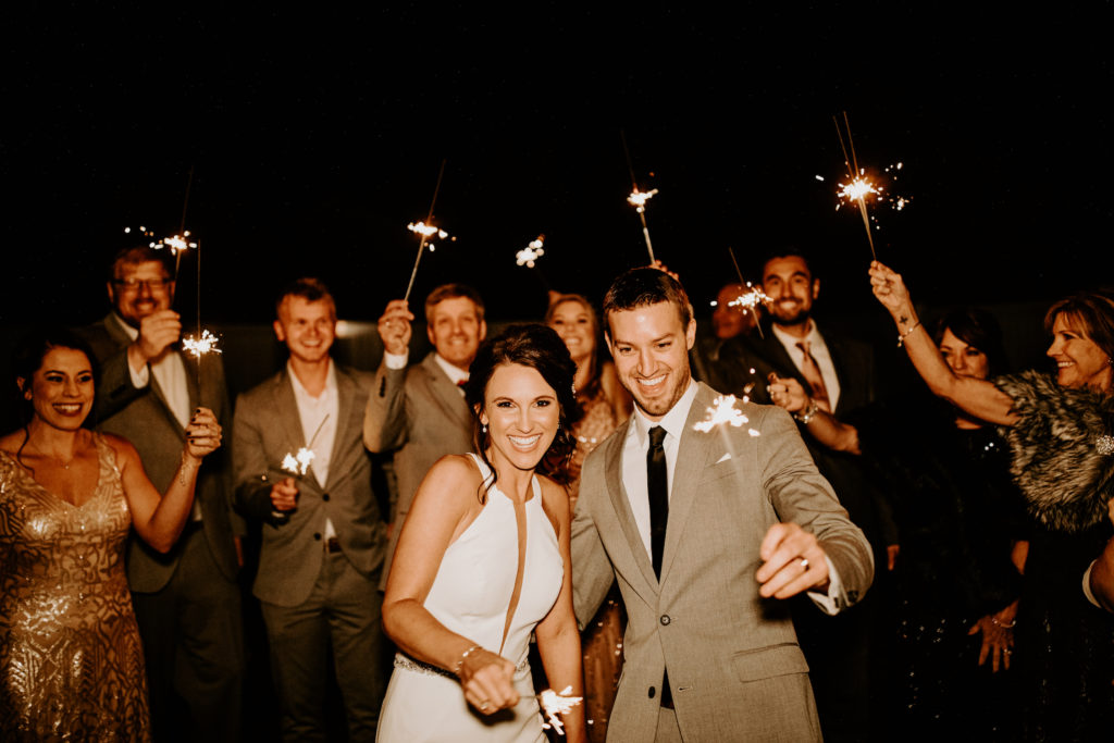bride and groom on wedding day lighting sparklers with their guests