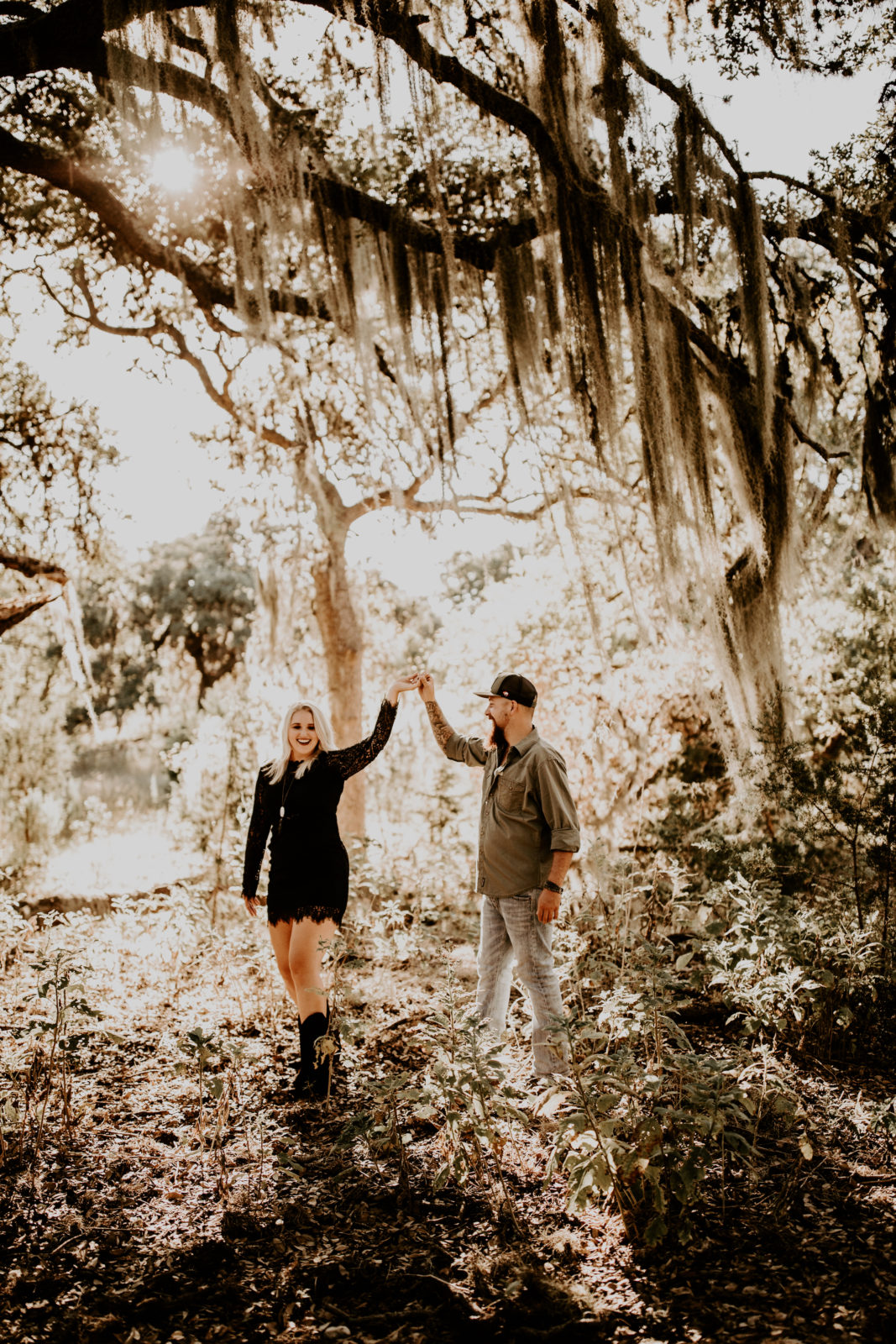 moody photo of man and woman dressed up dancing under the Texas Spanish moss
