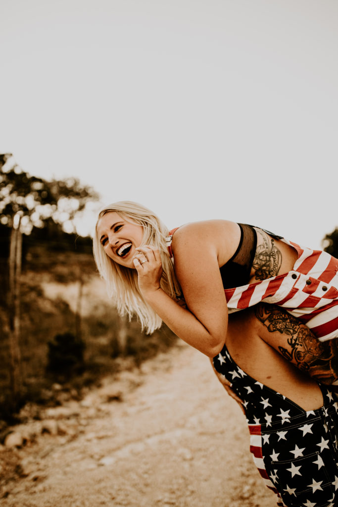woman laughing while man holds her up in American flag attire