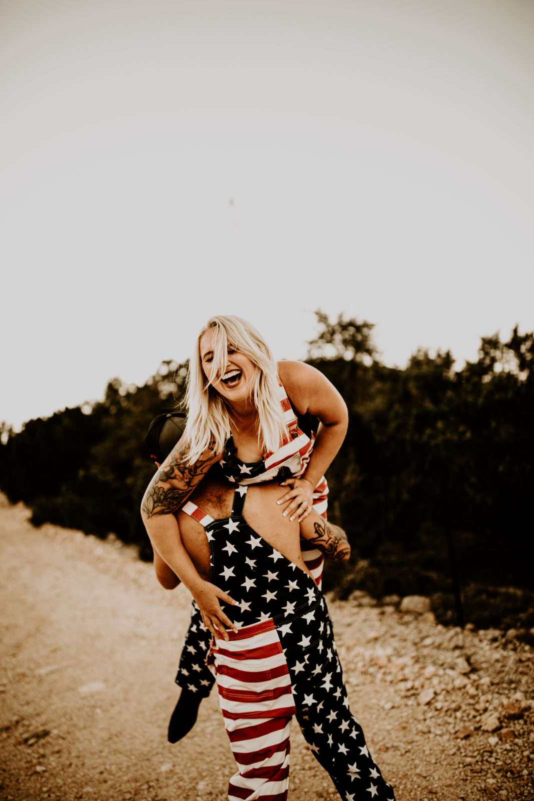 man holding woman up both in American flag tank tops
